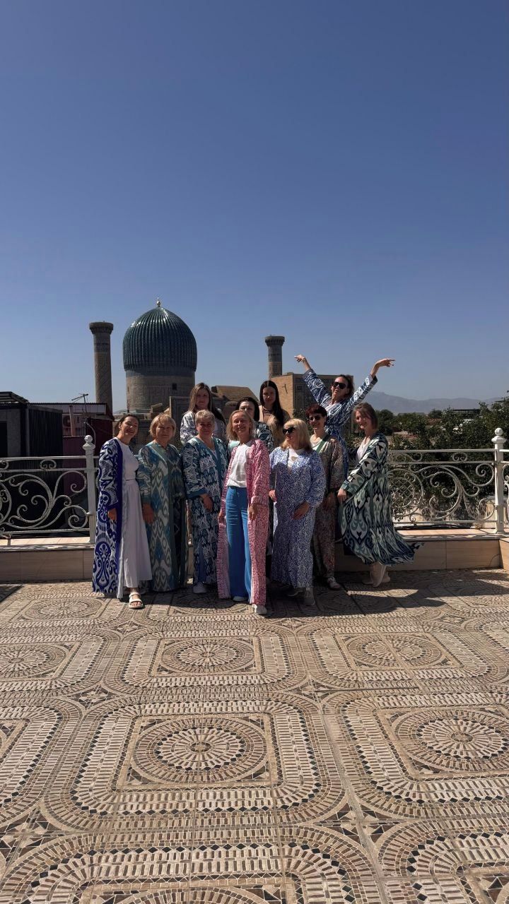 Un groupe de personnes se trouve sur une terrasse sur le toit, avec un sol à motifs et une structure en forme de dôme en arrière-plan.