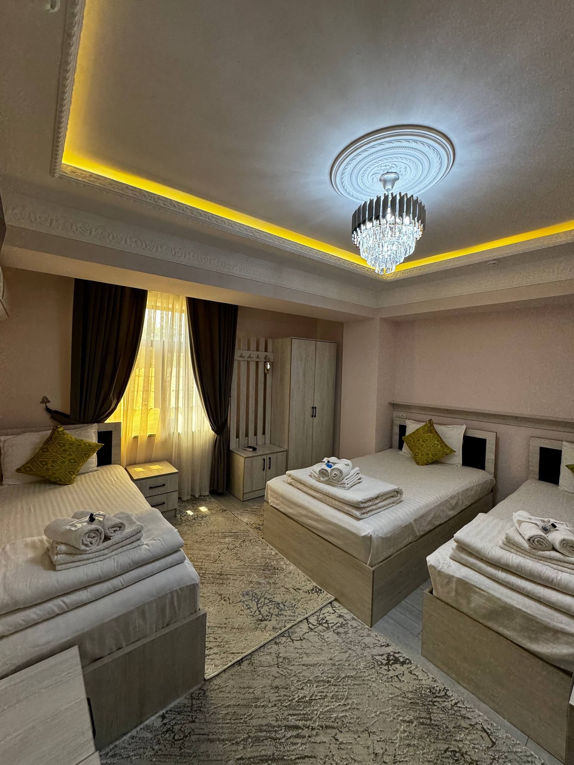 A hotel room with two beds, a chandelier, a wardrobe, and a desk.