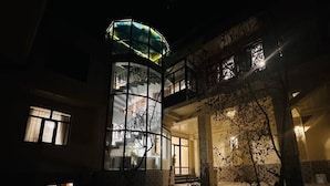 A multi-story building with a glass elevator shaft and a balcony.