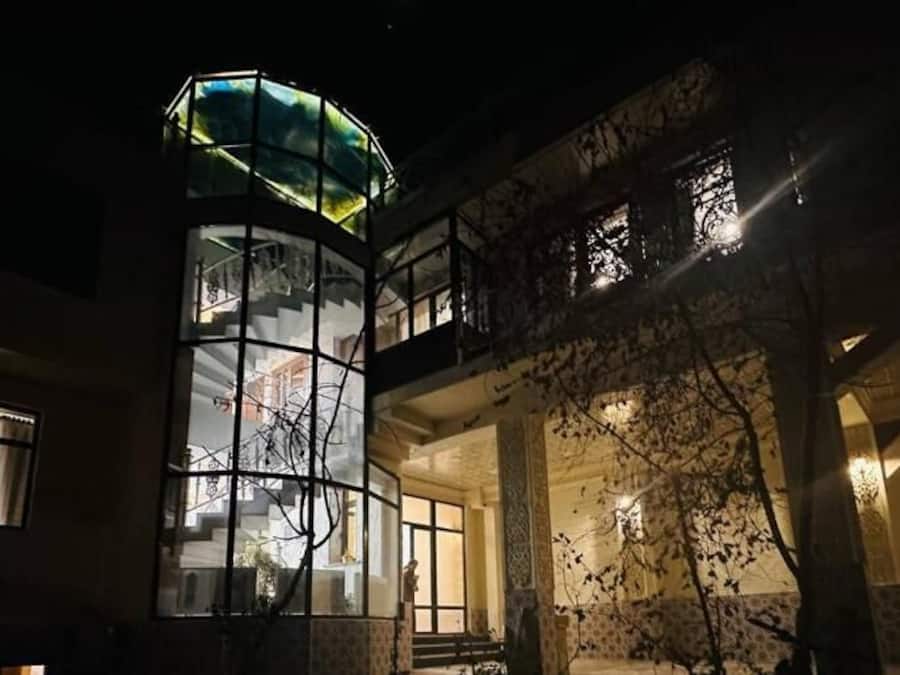 A multi-story building with a glass elevator shaft and a balcony.