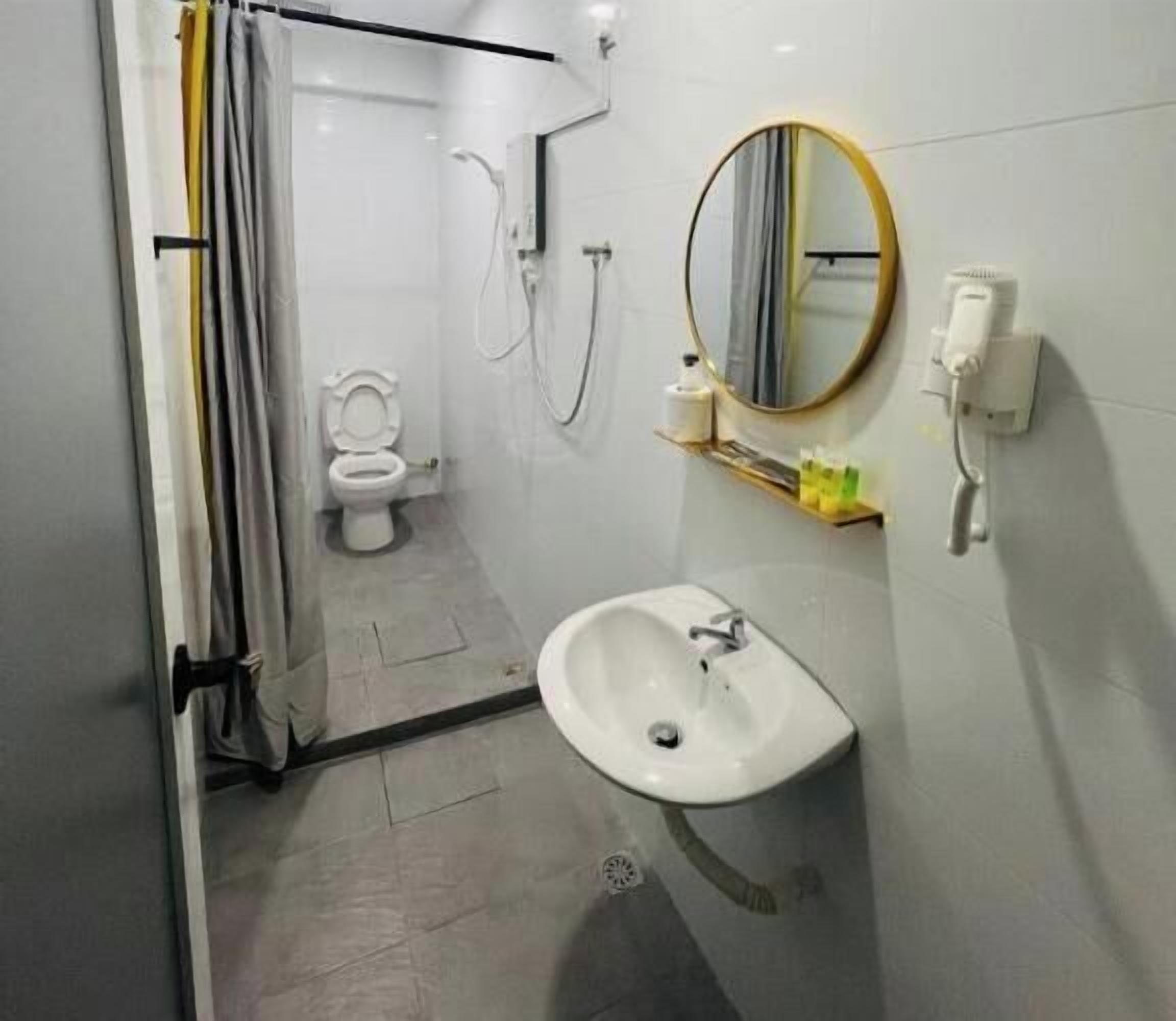 Een badkamer met een douchecabine van glas, toilet, wastafel en spiegel.