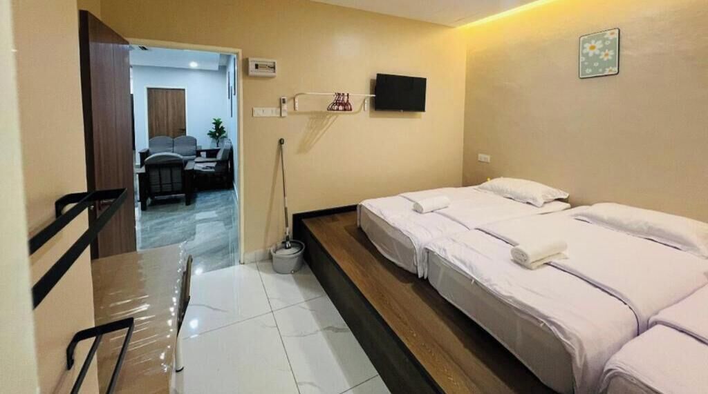 A hotel room with two beds, a TV mounted on the wall, and a desk with a chair.
