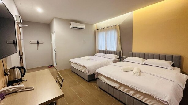 Habitación de hotel con dos camas, un escritorio con hervidor y unidad de aire acondicionado.