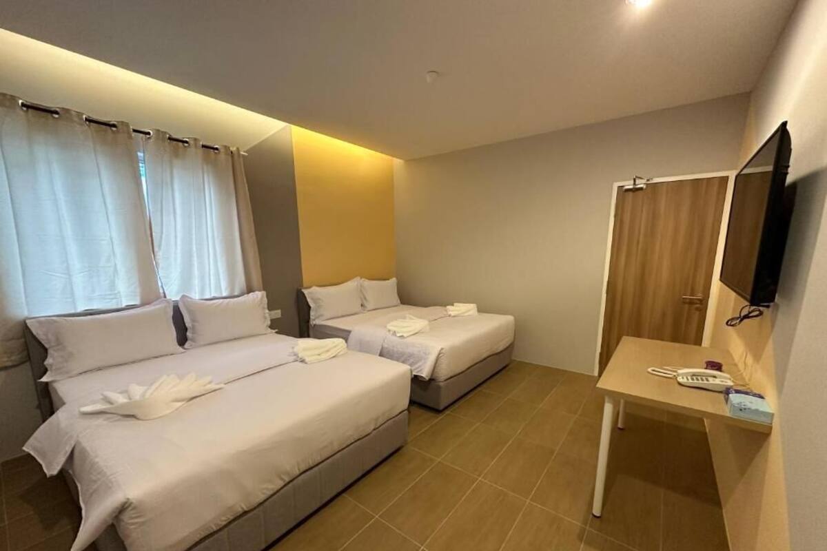 Ett hotellrum med två sängar, ett skrivbord med en telefon och en tv.