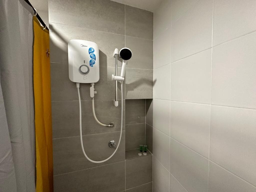 A shower with a handheld showerhead and a wall-mounted control panel.