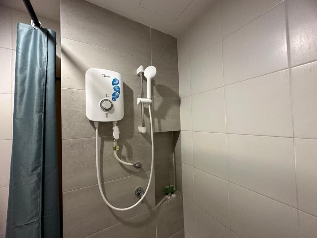 Un bagno con doccia, tenda e pareti piastrellate.