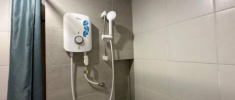 Un baño con ducha, cortina y paredes con azulejos.