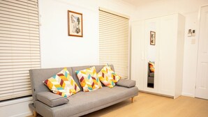 Un sofá gris con almohadones geométricos de colores, una puerta blanca y un cuadro en la pared.
