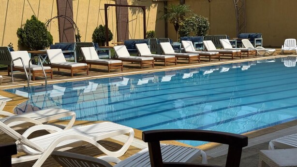 Una piscina con sillas de descanso y una pérgola.