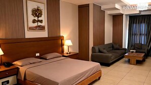Una habitación de hotel con una cama grande, un sofá, una mesita de café y una lámpara.