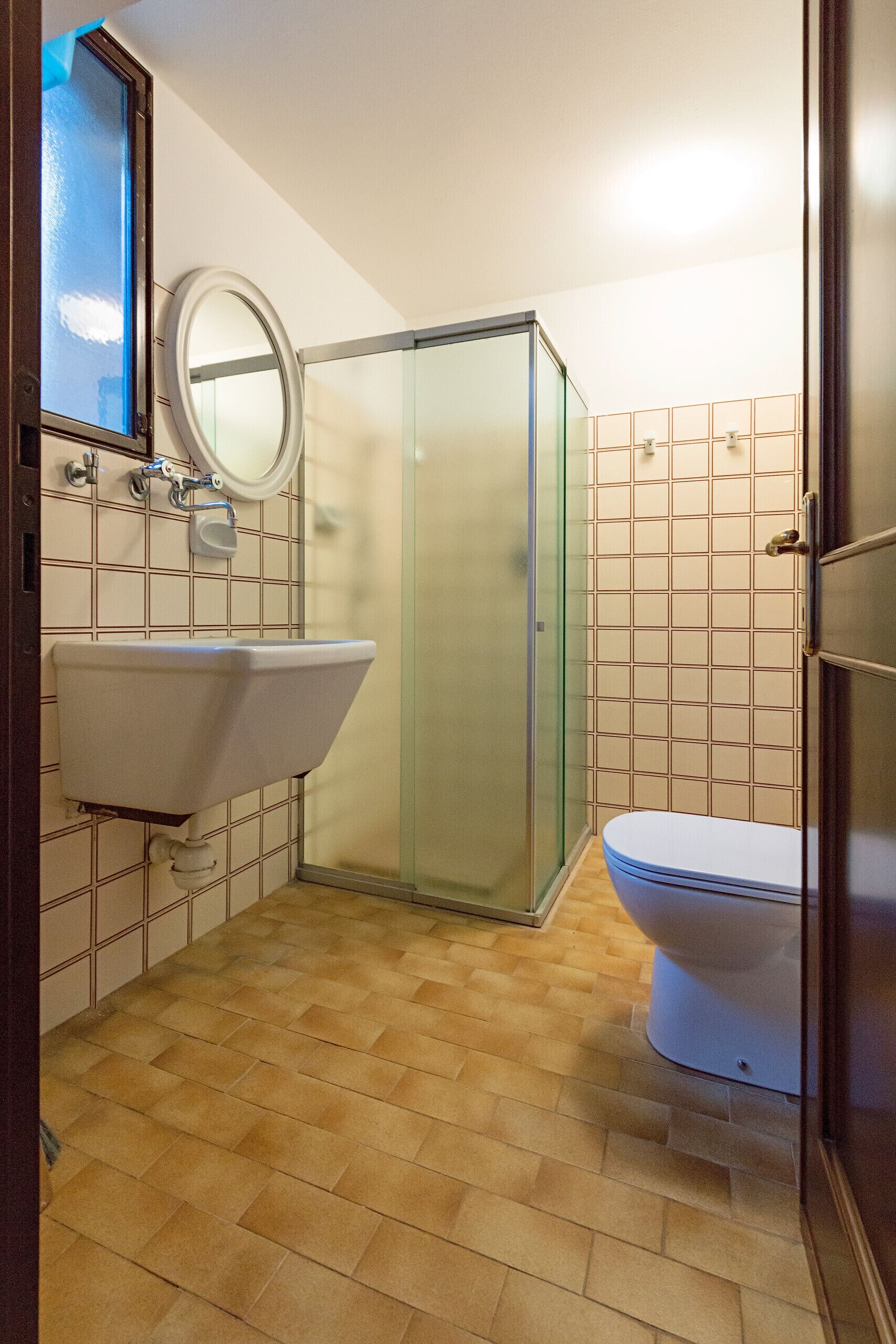 A bathroom with a sink, toilet, and glass shower enclosure.