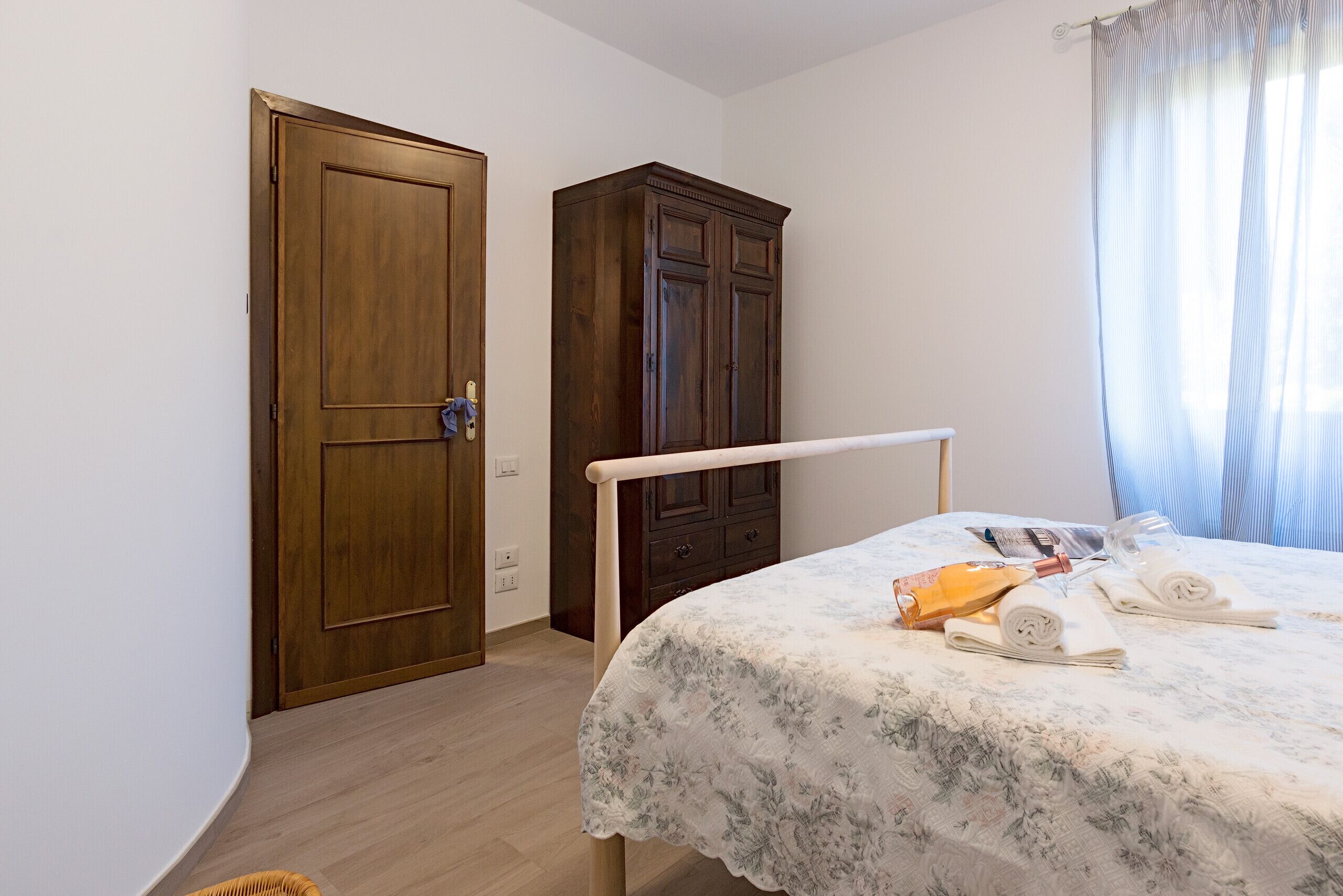 A bedroom with a bed, a wardrobe, and a door.