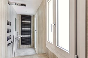 Ein schmaler Flur mit einem Waschbecken, einem Spiegel und einer Tür mit Fenster.