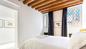 A bedroom with a bed, a radiator, a window with curtains, and framed pictures on the wall. - Dimora San Lorenzo – Central Venice 2BR with Private Courtyard (Venezia)