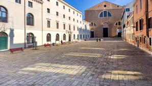 A courtyard with a central building, benches, and a clear sky. - Dimora San Lorenzo – Central Venice 2BR with Private Courtyard (Venezia)