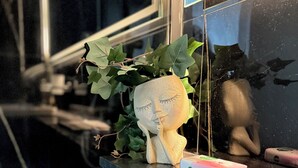 A desk with a plant, a figurine, and a skincare product. - Cozy 1-bedroom apartment in Dubai (Dubai)