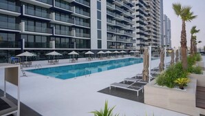 A modern hotel with a rooftop pool, sun loungers, and palm trees. - Cozy 1-bedroom apartment in Dubai (Dubai)