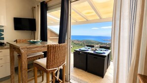 En matplats med ett bord och stolar, en tv och utsikt över havet.