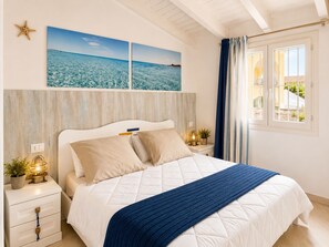 A bedroom with a bed, a nightstand, a wall-mounted shelf, a window with curtains, and a starfish decoration. - L' Ancora - Key to Villas (Paduledda)