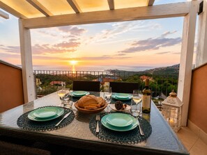A table set for two with a view of the sunset over a coastal landscape. - L' Ancora - Key to Villas (Paduledda)