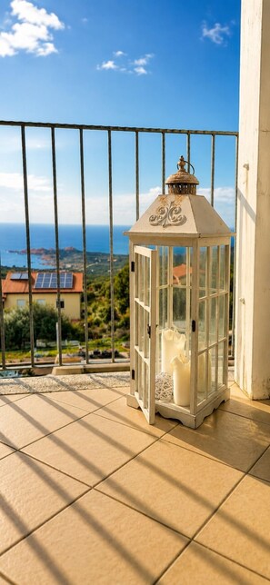A balcony with a white lantern, tiled floor, and a view of the sea and buildings. - L' Ancora - Key to Villas (Paduledda)