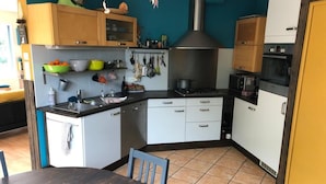 Een kleine keuken met een fornuis, magnetron en diverse keukengerei.