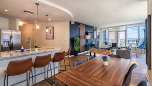 A modern kitchen with a bar area, a dining table with chairs, and a living area with a sofa and a hammock. - Downtown PHX Retreat Pool, Gym Balcony Views (Phoenix)