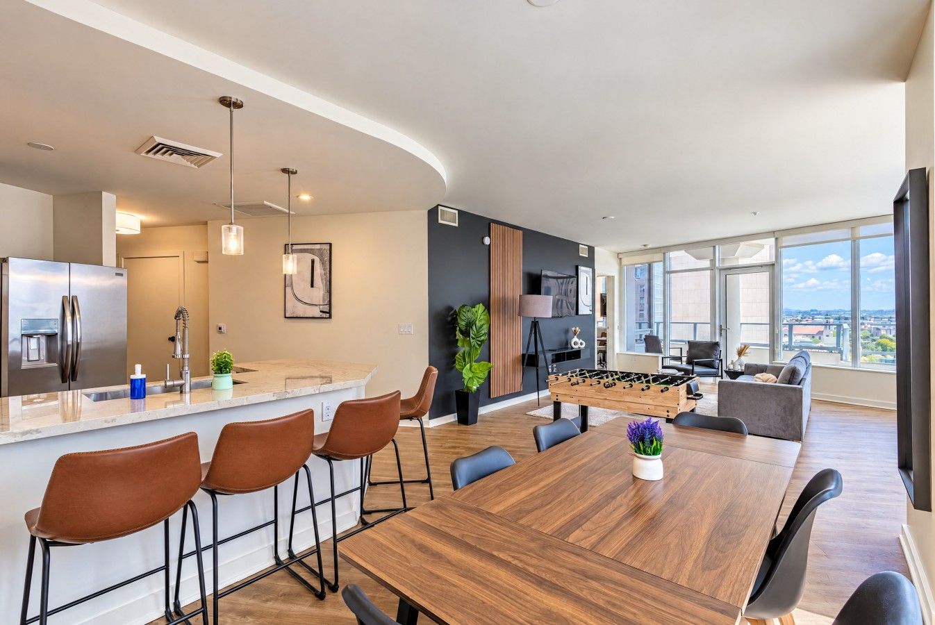 Una cocina moderna con una isla grande, taburetes de bar y una mesa de fútbol.