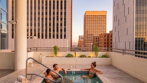 A rooftop pool with a view of tall buildings, a poolside area with a railing, and a few cacti. - Downtown PHX Retreat Pool, Gym Balcony Views (Phoenix)