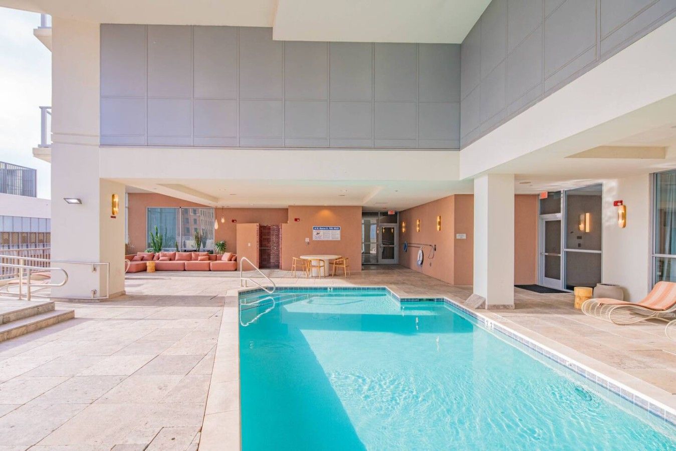 A hotel pool area with a seating area, a staircase, and a view of the building's interior.