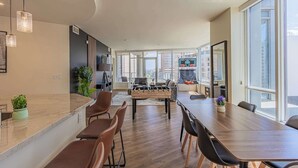 A spacious living area with a foosball table, a long dining table, and a kitchen area in the background. - Downtown PHX Retreat Pool, Gym Balcony Views (Phoenix)