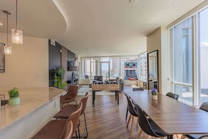 Amplia sala de estar con mesa de fútbol, una larga mesa de comedor y un área de cocina al fondo.