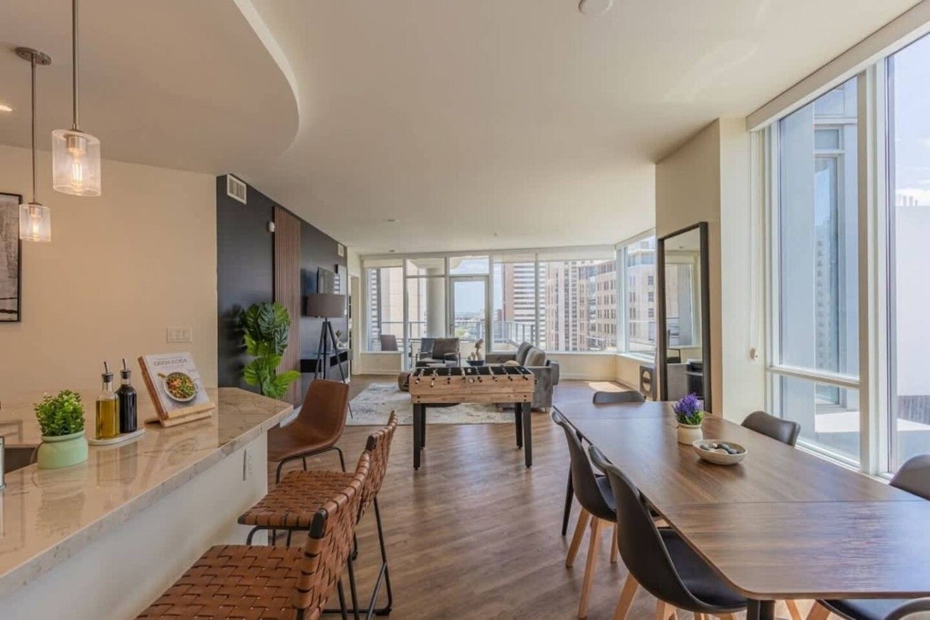 A modern apartment with a kitchen, dining area, and large windows offering city views.