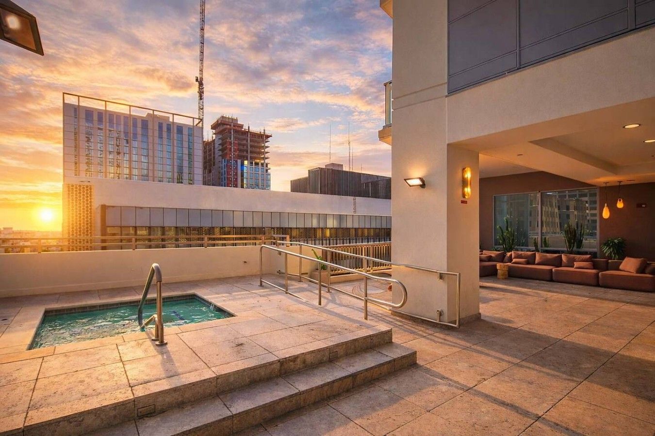 A rooftop pool area with a view of the city skyline at sunset.