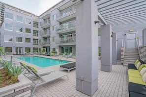 A modern building with a swimming pool, outdoor seating, and a staircase leading to an upper level. - Modern ASU Apt | Roosevelt Row | W/D + FreeParking (Phoenix)