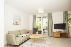 Een moderne woonkamer met een bank, salontafel en een televisie op een houten dressoir.