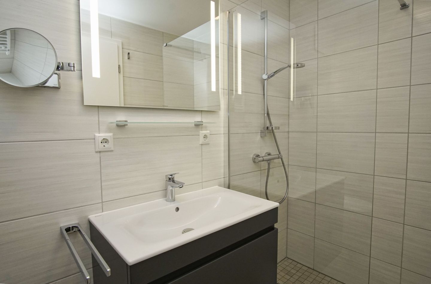 Ein modernes Badezimmer mit Waschbecken, Spiegel und Dusche.