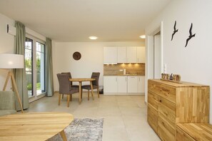 Eine moderne Küche mit weißen Schränken, einem Holzespeisetisch mit vier Stühlen und einer Holzkommode mit Schubladen.