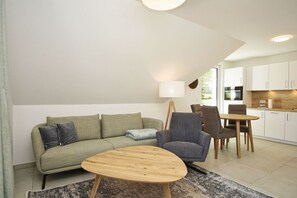 Ein modernes Wohnzimmer mit einer Couch, einem Couchtisch und einem Essbereich mit Stühlen und einem Tisch.