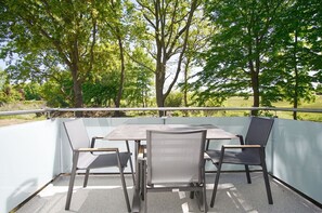 An outdoor patio with a table and chairs, surrounded by trees. - Beachfront apartment with balcony - Rex Rugia House 17 Apartment 08 - Beach resort (Mönchgut)