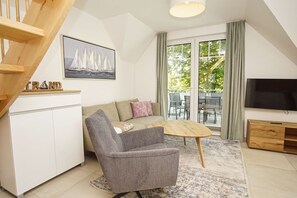 Ein modernes Wohnzimmer mit Sofa, Sessel, Couchtisch und Fernseher.