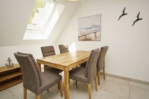Ein Essbereich mit einem Holztisch und sechs Stühlen, einem Vogelgemälde an der Wand und einem Oberlicht.