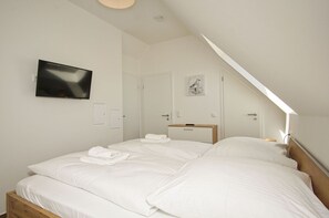 Ein Schlafzimmer mit zwei Betten, einem Fernseher und einem Oberlicht.