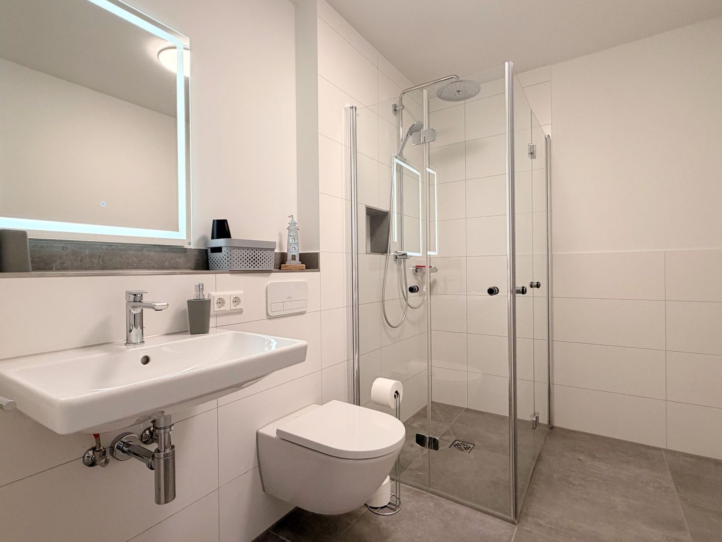 Ein modernes Badezimmer mit einer Duschkabine aus Glas, einem weißen Waschbecken und einer Toilette.