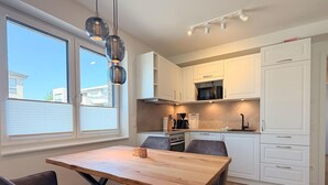 Eine moderne Küche mit weißen Schränken, einem Holztisch und Pendelleuchten.