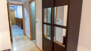 A hallway with a wooden floor, a sliding glass door, and a door with frosted glass panels.