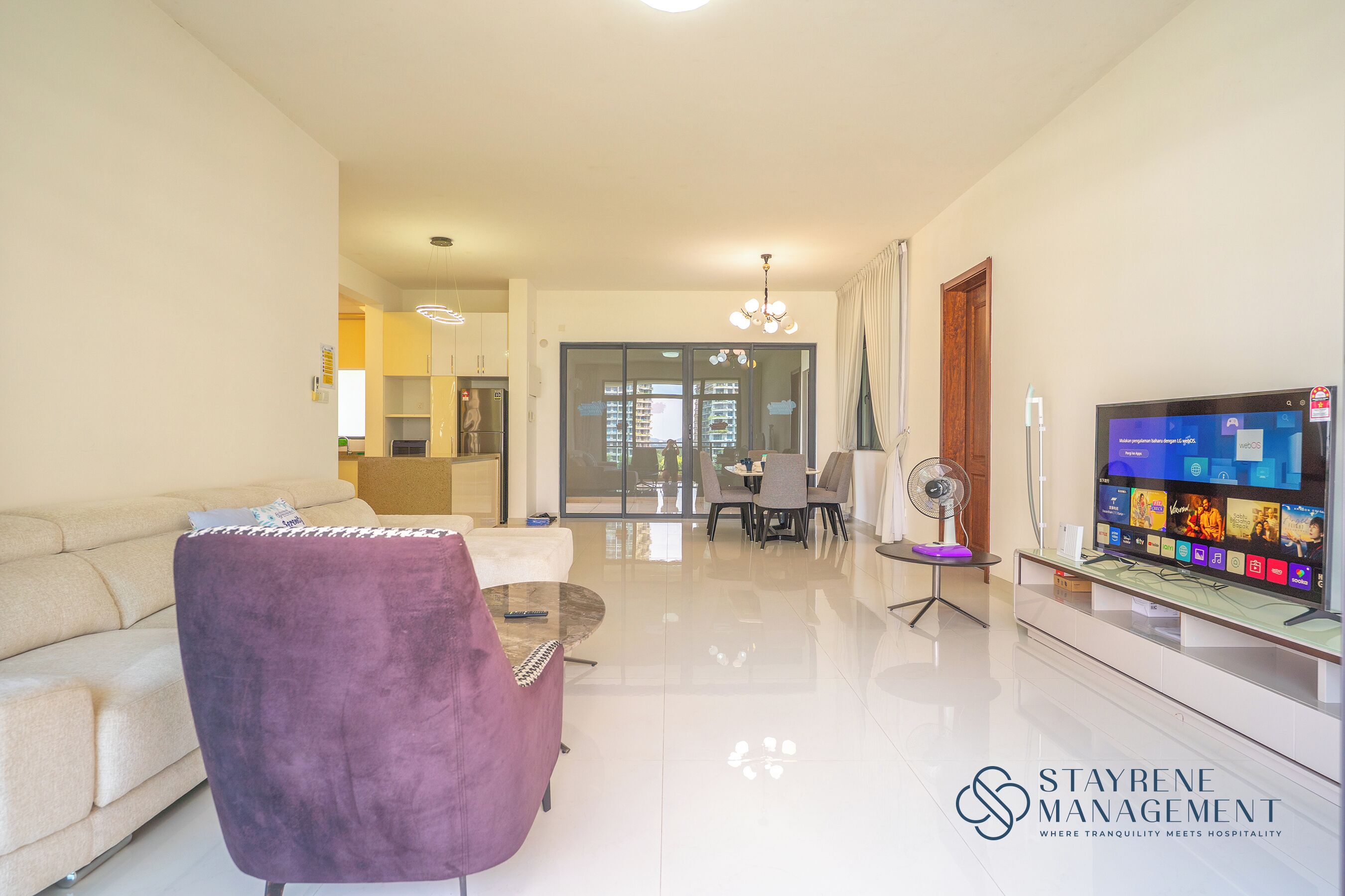 A modern living room with a sofa, a purple armchair, a dining table with chairs, a TV, and a glass cabinet.