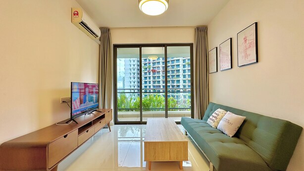 A modern living room with a television, sofa, coffee table, and a large window offering a view of high-rise buildings. - Casa Forest City JB by Stayrene (Gelang Patah)