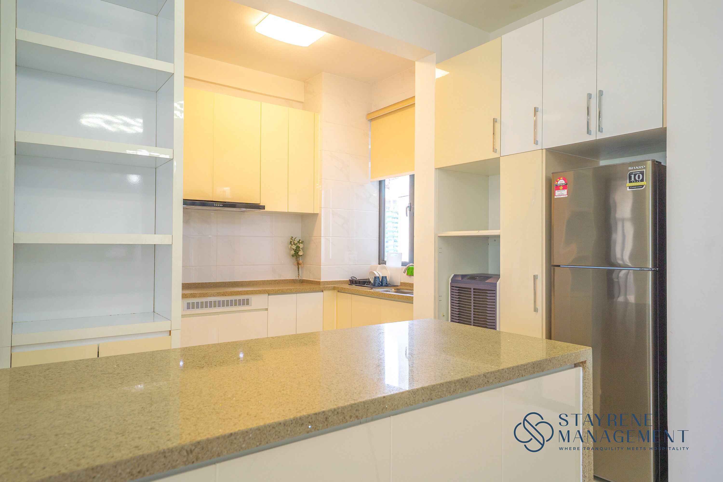 A modern kitchen with white cabinets, a stainless steel refrigerator, and a granite countertop.
