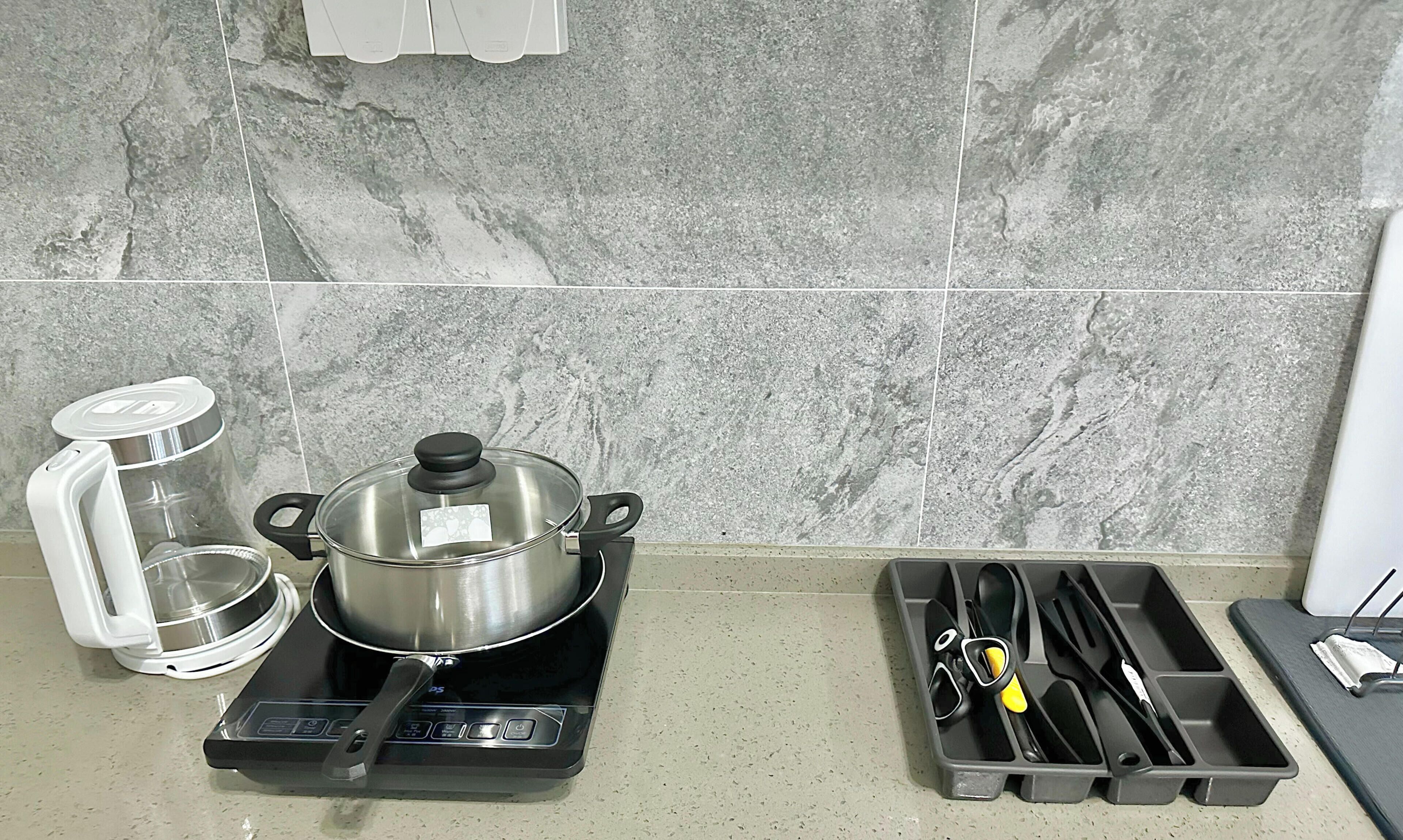 A kitchen with a gas stove, a pot on the stove, a kettle, and a utensil holder.